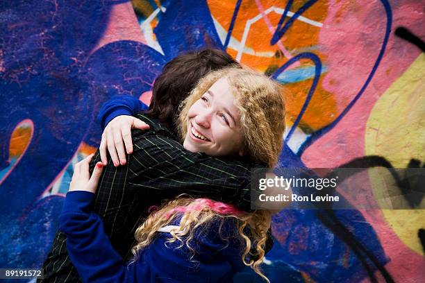 teen girl and boy hugging by graffitti wall - tag 14 photos et images de collection