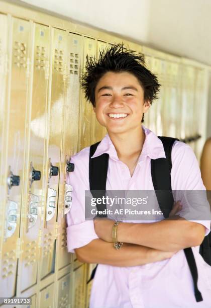 teen boy leans against lockers - one asian american boy smiling teen fotografías e imágenes de stock