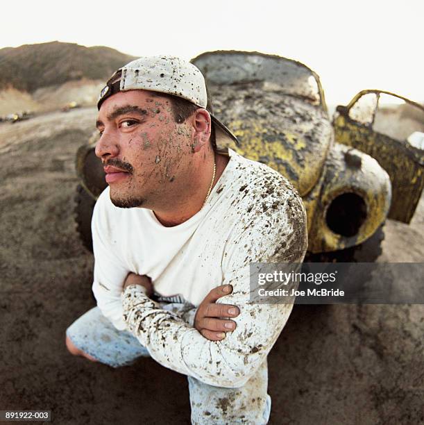 man squatting in front of car covered in mud - people covered in mud stock pictures, royalty-free photos & images