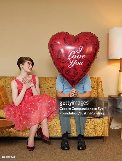 woman sitting beside man with heart-shaped balloon - love you stockfoto's en -beelden