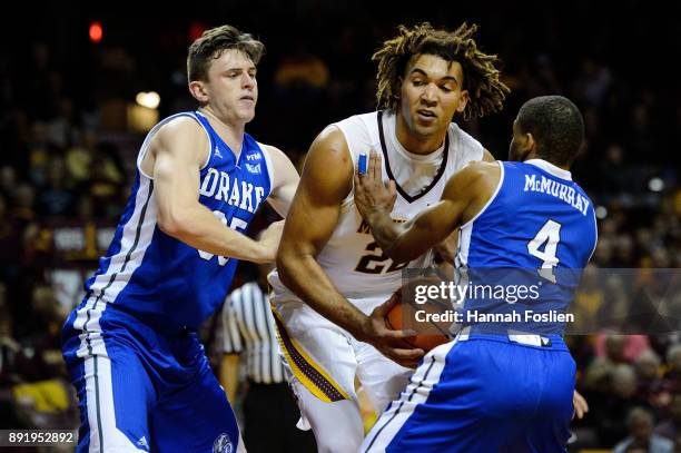 Nick McGlynn and De'Antae McMurray of the Drake Bulldogs defend against Reggie Lynch of the Minnesota Golden Gophers during the game on December 11,...