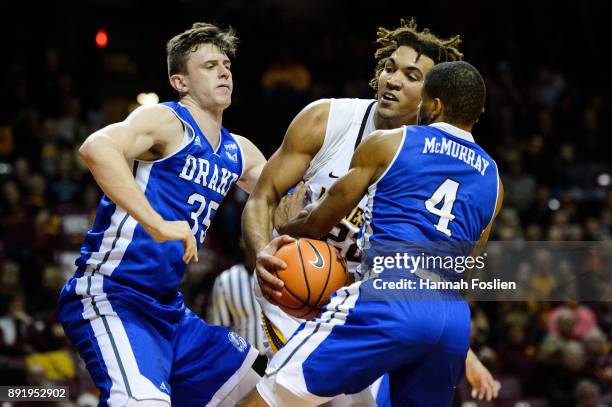 Nick McGlynn and De'Antae McMurray of the Drake Bulldogs defend against Reggie Lynch of the Minnesota Golden Gophers during the game on December 11,...