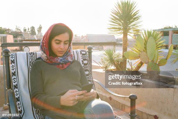 arab youth: young moroccan woman looking at smart phone - north africa stock pictures, royalty-free photos & images
