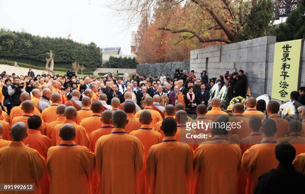 This photo taken on December 13, 2017 shows monks praying during a religious assembly to commemorate victims of Nanjing Massacre in front a memorial...
