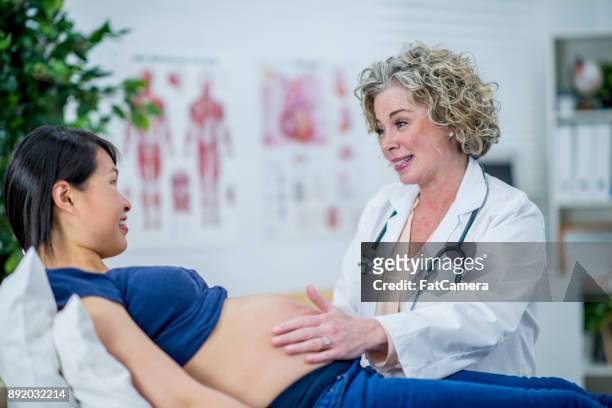 checking a pregnant woman's stomach - prenatal care stock pictures, royalty-free photos & images