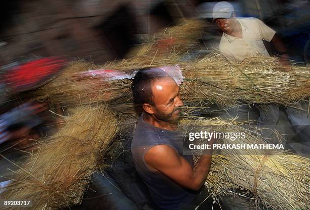 Nepalese man carries a straw effigy of Ghanta Karna to be burnt during the celebrations of the Hindu festival of "Gathemangal", also known as Ghanta...