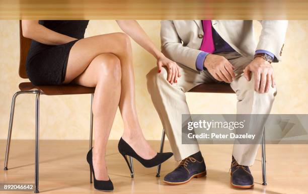 girl with her hand on a man's knee under the table - affairs stockfoto's en -beelden