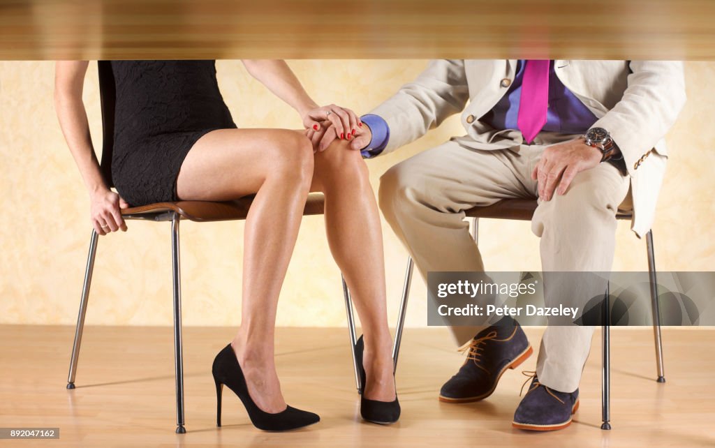 COUPLE HOLDING HANDS UNDER THE TABLE