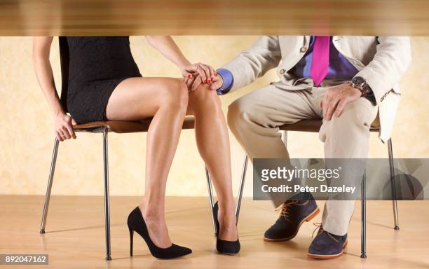 couple holding hands under the table - footsie under table stock pictures, royalty-free photos & images