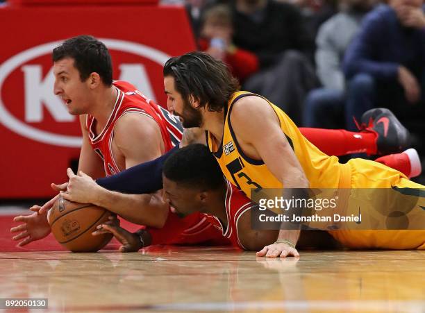 Paul Zipser and David Nwaba of the Chicago Bulls battle for a loose ball with Ricky Rubio of the Utah Jazz at the United Center on December 13, 2017...