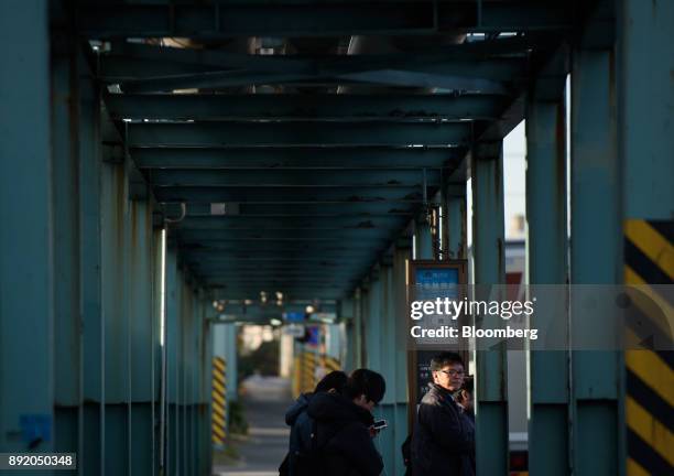 People wait at a bus stop in the Keihin industrial area of Kawasaki, Kanagawa Prefecture, Japan, on Tuesday, Dec. 12, 2017. The Bank of Japan will...