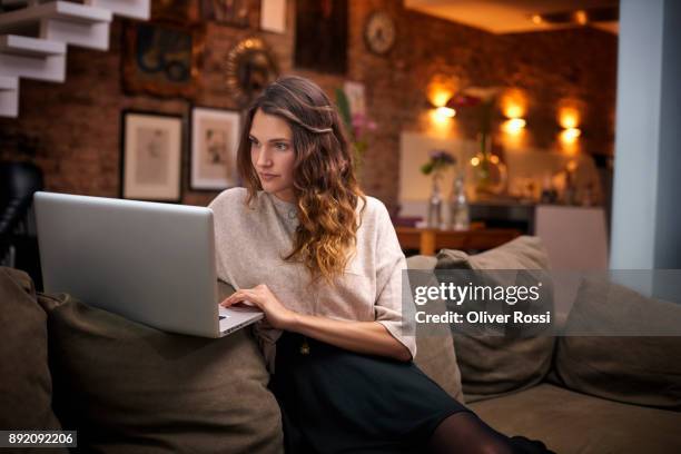 woman using laptop on couch at home - women wearing black stockings stock-fotos und bilder