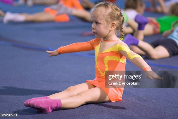 a small child gymnast following instructions - acrobatiek stockfoto's en -beelden