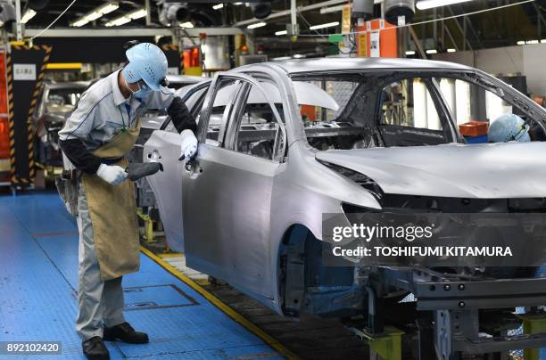 This December 8, 2017 picture shows workers assembling fourth generation Toyota Prius cars on the production line at the company's Tsutsumi assembly...