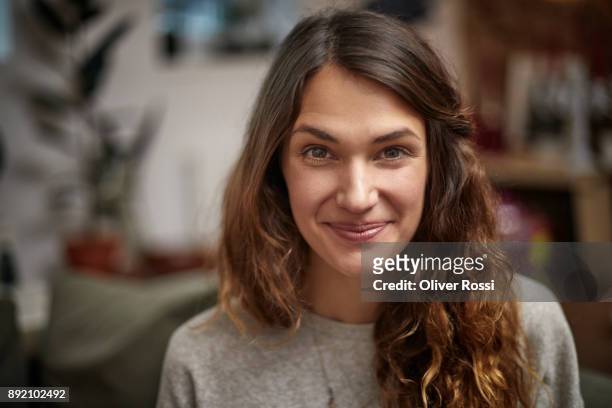 portrait of smiling brunette woman at home - langes haar stock-fotos und bilder