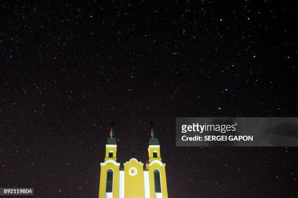 Meteor streaks across the sky behind a Catholic church during the annual Geminid meteor shower in the village of Krevo, some 100 km northwest of...