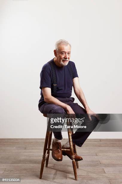 portrait of old man sitting on chair - sitzen stock-fotos und bilder