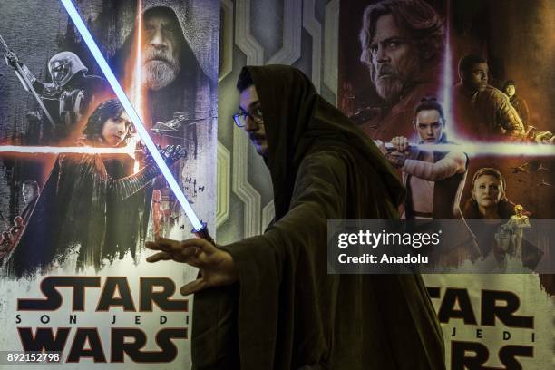 Fan poses for a photo with a lightsaber during a gathering for the latest of the Star Wars film series "Star Wars: The Last Jedi" movie in Istanbul,...