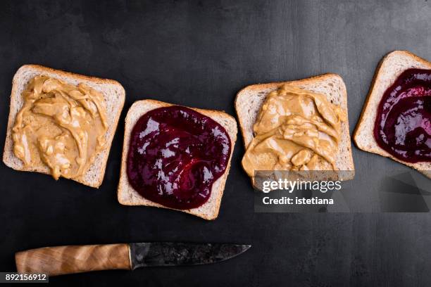 making peanut butter and jelly sandwiches - beurre de cacahuètes photos et images de collection