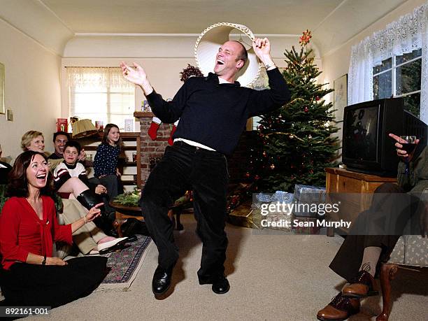 man dancing around with lamp shade on head, surrounded by family - christmas funny stockfoto's en -beelden