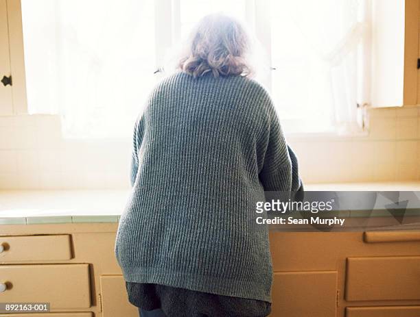 mature woman standing in front of kitchen sink, rear view - woman front and back stockfoto's en -beelden