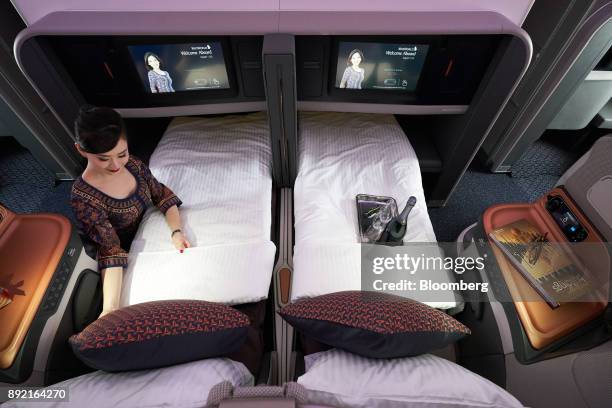 Flight attendant arranges a business class seat of a Singapore Airlines Ltd. Airbus SE A380 aircraft with refitted cabins during a media tour at...