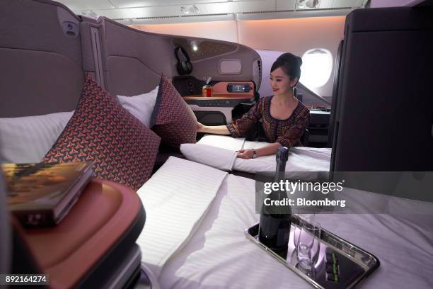 Flight attendant arranges a business class seat of a Singapore Airlines Ltd. Airbus SE A380 aircraft with refitted cabins during a media tour at...