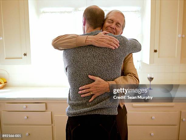 father and son embracing in kitchen - proud father stock pictures, royalty-free photos & images