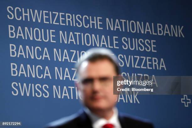 The Swiss National Bank logo sits on a wall behind Thomas Jordan, president of the Swiss National Bank , as he pauses during the bank's rate...