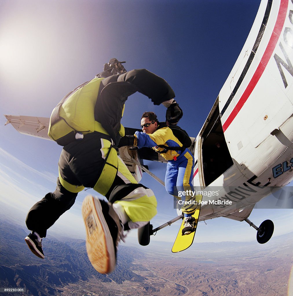 Two skysurfers jumping out of plane