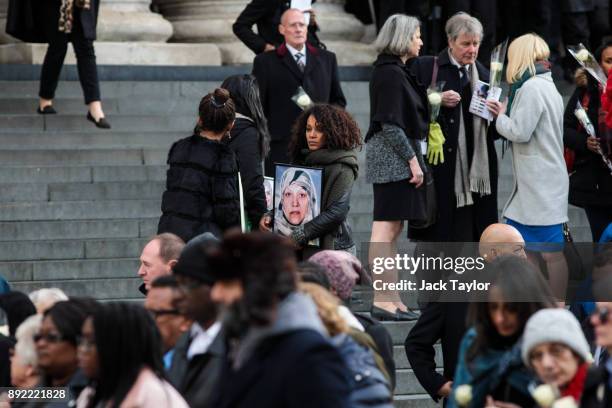 Mourners carry pictures of the victims of the Grenfell fire and flowers as they leave a national memorial service held at St Paul's Cathedral on...