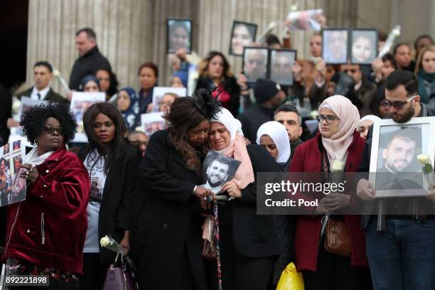 Mourners hold up photogrpahs of victims as they leave the Grenfell Tower National Memorial service at St Paul's cathedral on December 14, 2017 in...