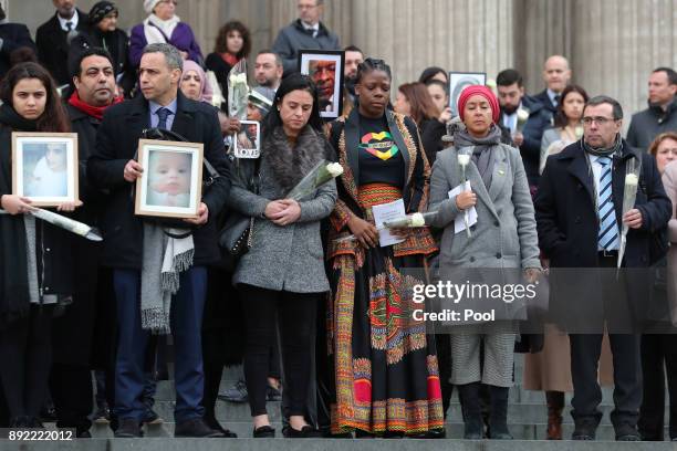Mourners hold up photogrpahs of victims as they leave the Grenfell Tower National Memorial service at St Paul's cathedral on December 14, 2017 in...