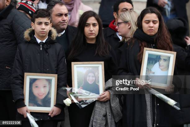 Mourners hold up photogrpahs of victims as they leave the Grenfell Tower National Memorial service at St Paul's cathedral on December 14, 2017 in...