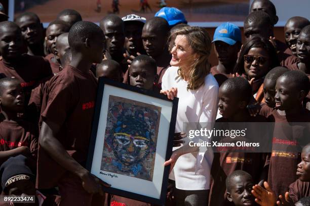 Queen Letizia of Spain receives a gift as she visits Village Pilote initiative for kids of the streets on December 14, 2017 in Dakar, Senegal. Queen...