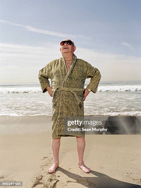 mature man on beach wearing sun glasses and leopard print robe - bathrobe stockfoto's en -beelden