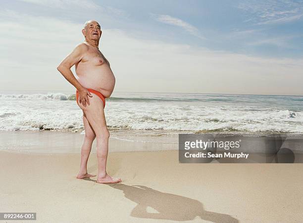 mature man wearing swimsuit on beach - fat man on beach stock pictures, royalty-free photos & images