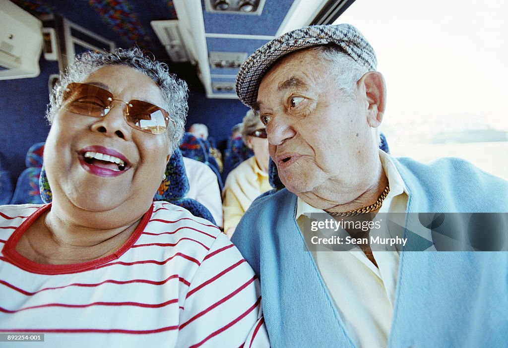 Mature couple on tour bus, smiling