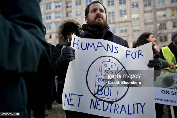 Demonstrator opposed to the roll back of net neutrality rules holds a "Humans For New Neutrality" sign outside the Federal Communications Commission...