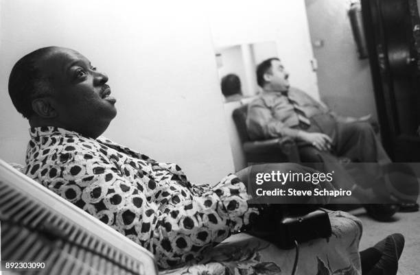 Backstage at the Apollo Theater, American Jazz musician and bandleader Count Basie , in a dressing gown, sits with a telephone on the arm of his...