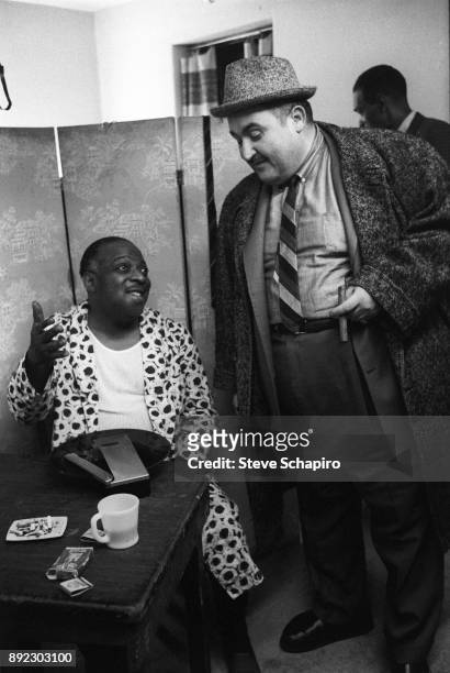 Backstage at the Apollo Theater, American Jazz musician and bandleader Count Basie , in a dressing gown, speaks with an unidentified man, New York,...