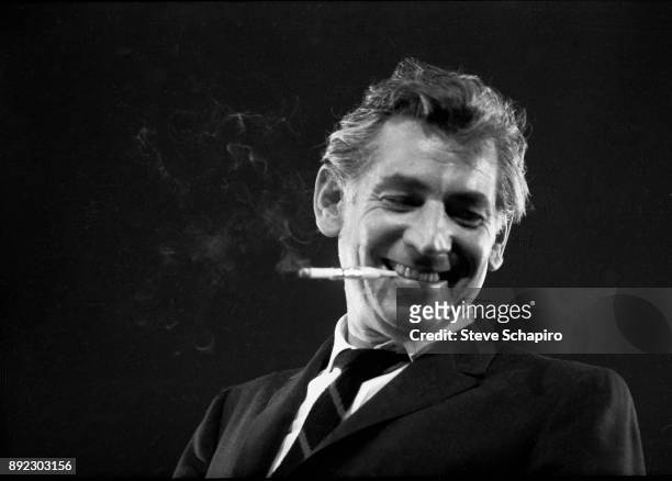 View of American composer, musician, and conductor Leonard Bernstein , a cigarette in his mouth, as he conducts at Carnegie Hall, New York, New York,...