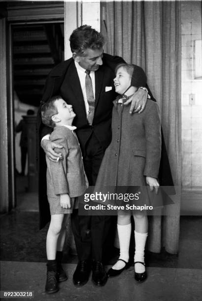 Backstage at Carnegie Hall, American composer, musician, and conductor Leonard Bernstein smiles and embraces his children, Alexander and Jamie...