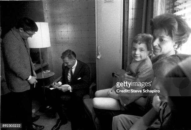 As an unidentified man watches, American composer, musician, and conductor Leonard Bernstein signs an autograph backstage at Carnegie Hall, New York,...