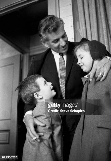 Backstage at Carnegie Hall, American composer, musician, and conductor Leonard Bernstein smiles and embraces his children, Alexander and Jamie...