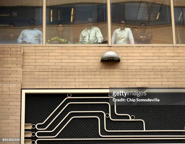 Federal Communication Commission employees look out their building's windows and watch as demonstrators protest against the end of net neutrality...
