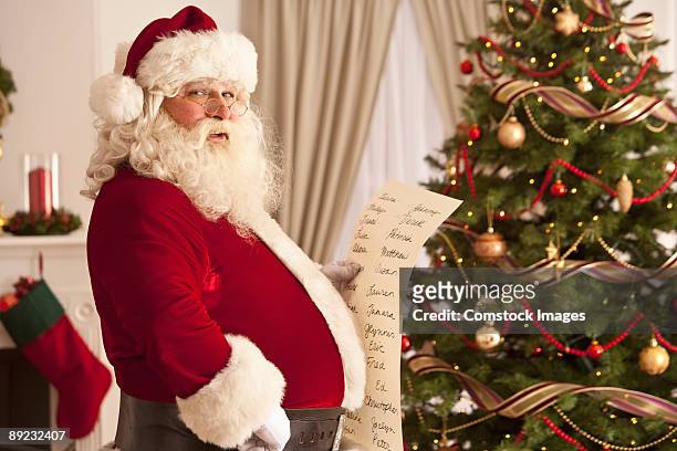 santa clause checking his naughty and nice list. - naughty christmas ornaments stock pictures, royalty-free photos & images
