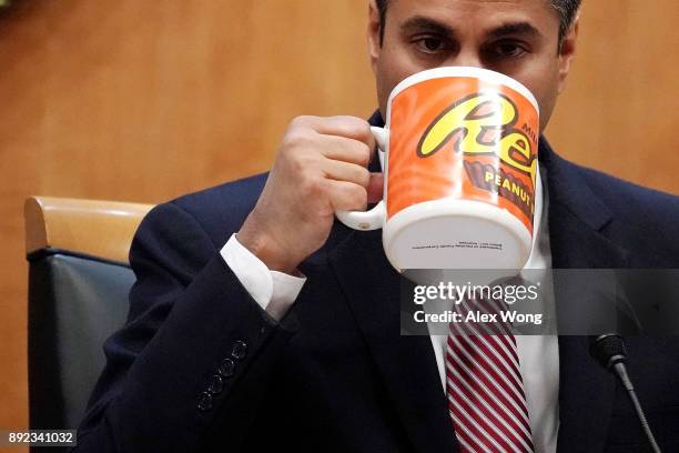 Federal Communications Commission Chairman Ajit Pai drinks from a big coffee cup during a commission meeting December 14, 2017 in Washington, DC. The...