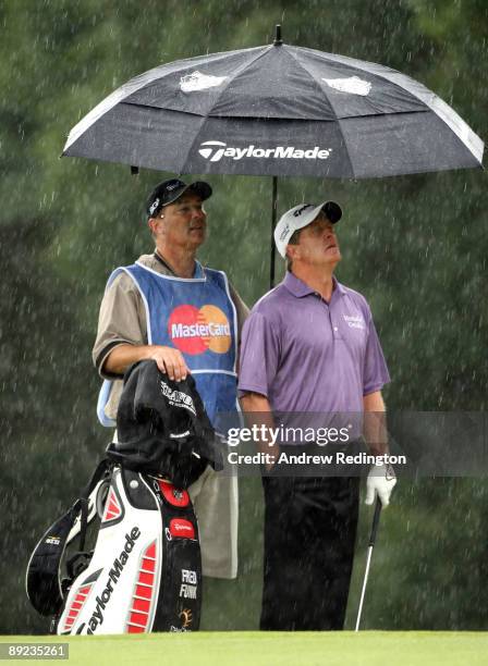 Fred Funk of the USA and his caddie wait in the rain on the ninth hole during the second round of The Senior Open Championship presented by...