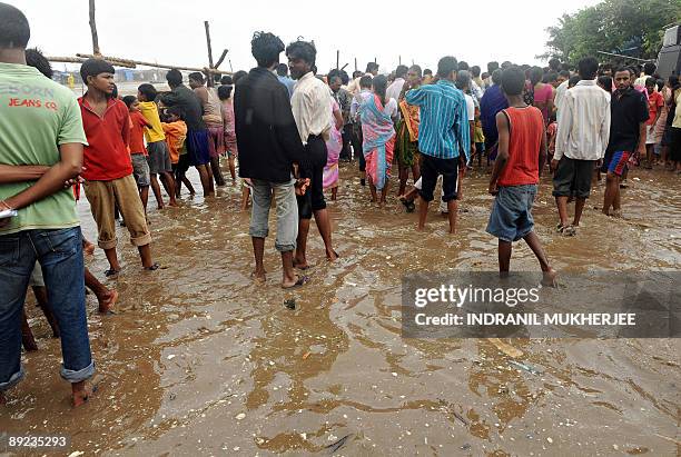 Shantytown residents on Versova beach, stand behind a temporary barricade on high ground in ankle deep sea water as they wait for the seasons's...